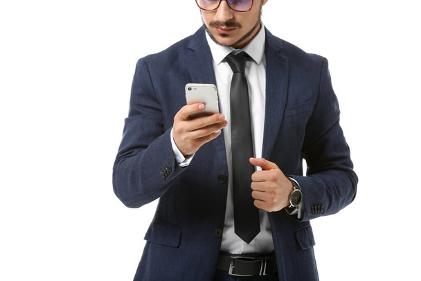 Όμορφος νεαρός επιχειρηματίας με κινητό τηλέφωνο σε λευκό φόντο - Φωτογραφία, εικόνα
