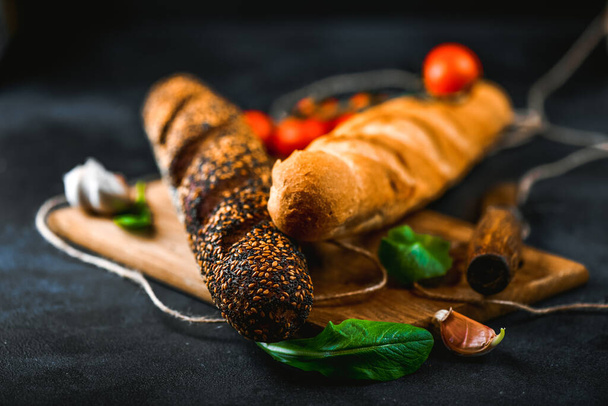 Rye and wheaten baguette on cutting board. Pumpernickel brown and white bread closeup. - Foto, immagini