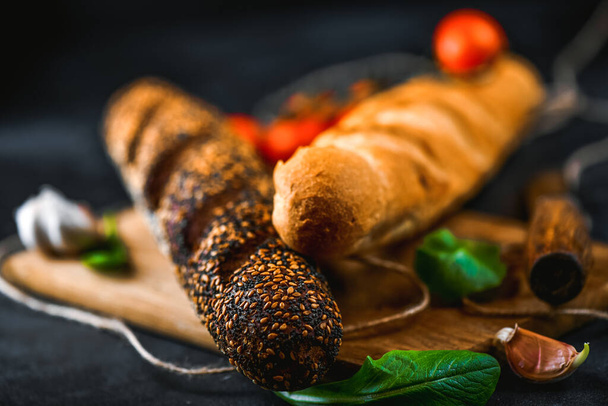 Rye and wheaten baguette on cutting board. Pumpernickel brown and white bread closeup. - Foto, immagini