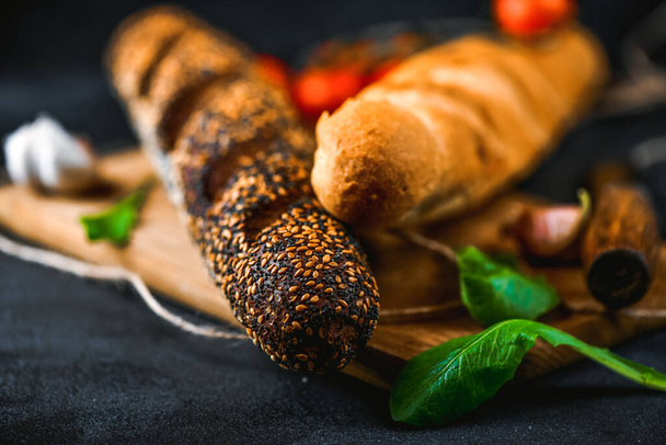 Rye and wheaten baguette on cutting board. Pumpernickel brown and white bread closeup. - Foto, Bild