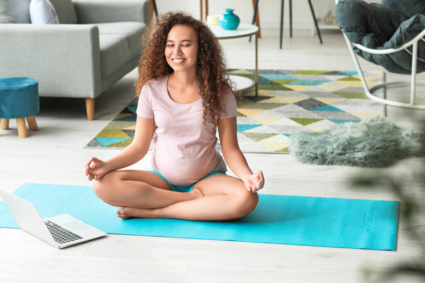 Young pregnant woman practicing yoga at home - Foto, Imagem