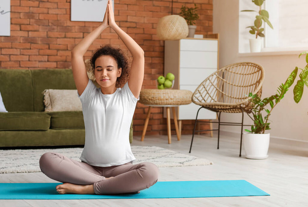Jeune femme enceinte pratiquant le yoga à la maison - Photo, image