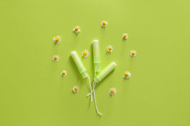 Menstrual tampons with chamomile flowers on color background - Photo, Image