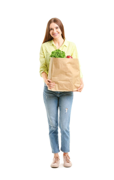 Νεαρή γυναίκα κρατώντας τσάντα με φαγητό σε λευκό φόντο - Φωτογραφία, εικόνα