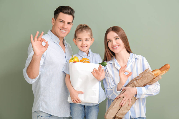 Gezin met eten in zak tonen OK gebaar op kleur achtergrond - Foto, afbeelding