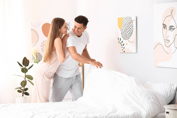 Morning of happy young couple changing bedclothes at home - Foto, afbeelding