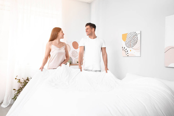 Morgen eines glücklichen jungen Paares, das zu Hause die Bettwäsche wechselt - Foto, Bild