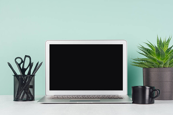 Modern business interior - workplace with blank computer display, black stationery, coffee cup, succulent potted plant in light green mint menthe interior on white wood desk. - Φωτογραφία, εικόνα