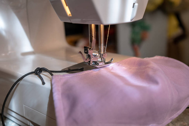 coser una mascarilla en casa debido a la epidemia de covid-19, máquina de coser de cerca con tela de algodón
 - Foto, Imagen