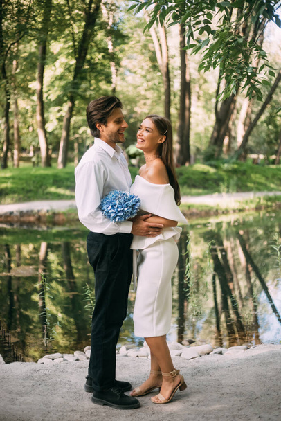 Net getrouwd stel omarmt staan in de buurt van het meer in park - Foto, afbeelding