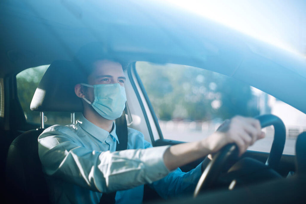 Young man  in protective sterile medical mask sits in the car during an epidemic in quarantine city. Health protection, safety and pandemic concept. Covid - 19. - Foto, immagini