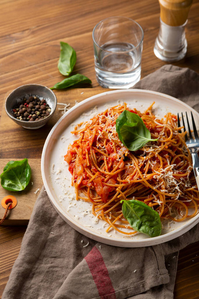 Spaghettis de blé entier avec sauce rouge sur plaque blanche vue du dessus sur table en bois
 - Photo, image