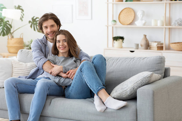 Giovane bella coppia in posa sul divano a casa
 - Foto, immagini