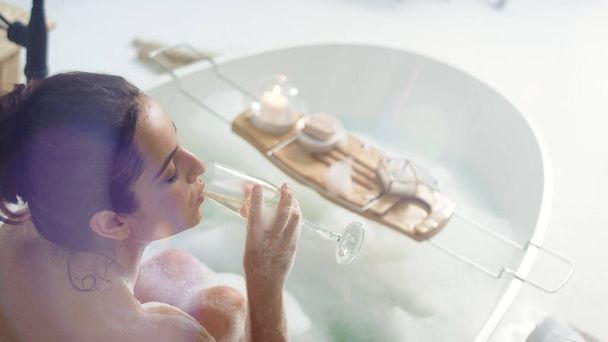 Romantikus nő pezsgőt iszik a luxus fürdőben. Szexi lány pihentető fürdőkádban. - Fotó, kép