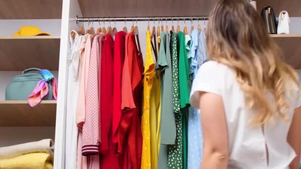 Mladá žena vybírá oblečení ze skříně doma - Záběry, video
