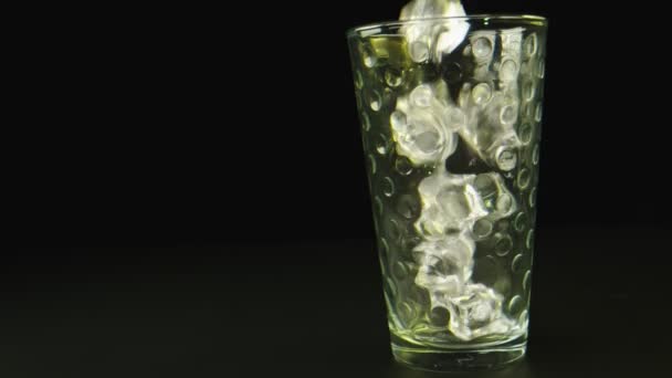 Makro-Nahaufnahme von Eis, das auf ein Glas fällt. Hintergrund ist schwarz. - Filmmaterial, Video