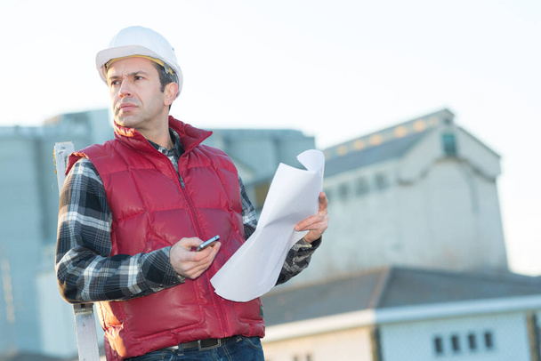 man with hardhat holding pieces of paper - Photo, Image