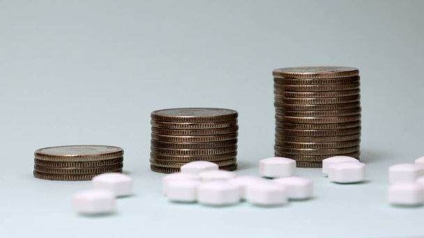 Three piles of coins and white pills. - Valokuva, kuva