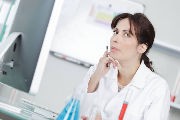 female scientist sat at computer with contemplative expression - Photo, Image