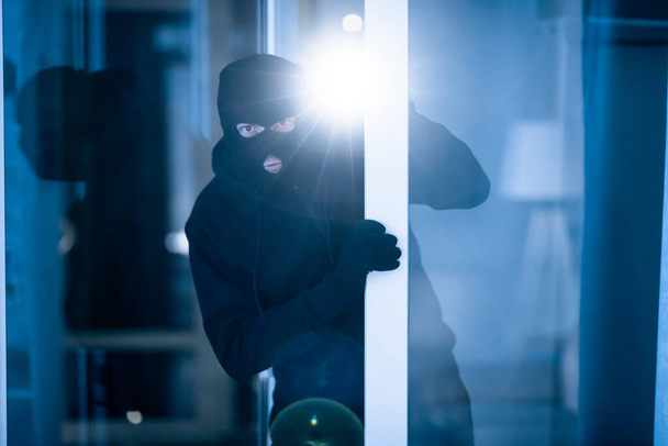 Thief breaking into apartment to steal, using torch - Foto, afbeelding
