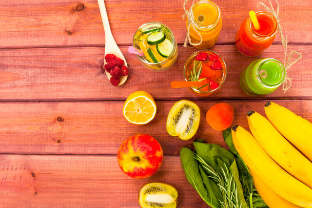 Fresh detox juices in glass bottles on the wooden background. Fruits and berries. Lifestyle, vegan food and drink, health care, diet and summer concept. Top view. Close up. - Foto, imagen