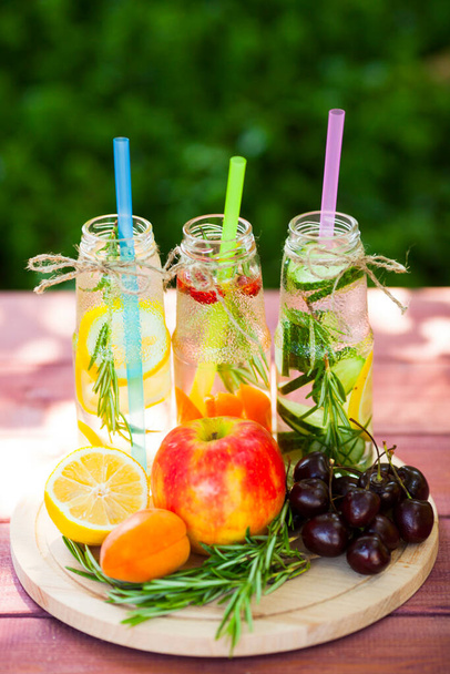 Fresh detox juices in glass bottles on the wooden background. Fruits and berries. Lifestyle, vegan food and drink, health care, diet and summer concept. Top view. Close up - Photo, Image