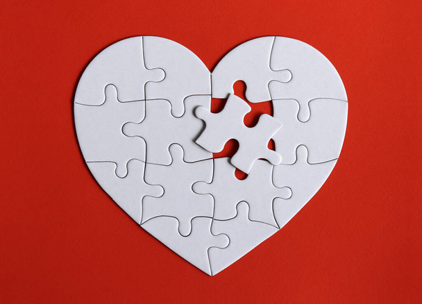 Puzzles in the shape of a white heart on the red background. - Photo, Image