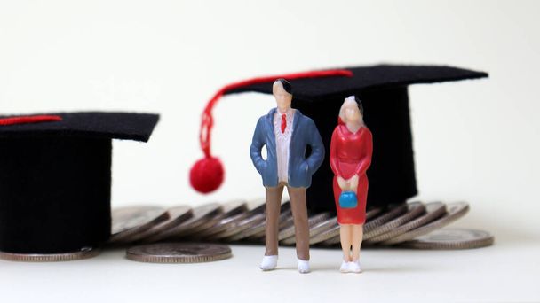 Two graduation cap on the coins and miniature people. - Photo, Image