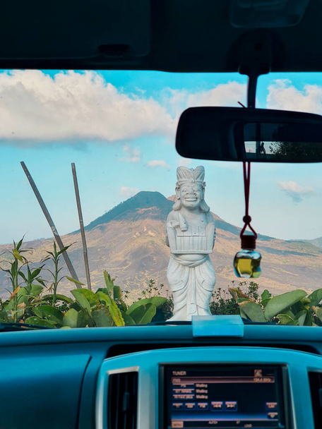 Вид на стародавню балістичну скульптуру з великим вулканом Кінтамані на задньому плані зсередини автомобіля
 - Фото, зображення