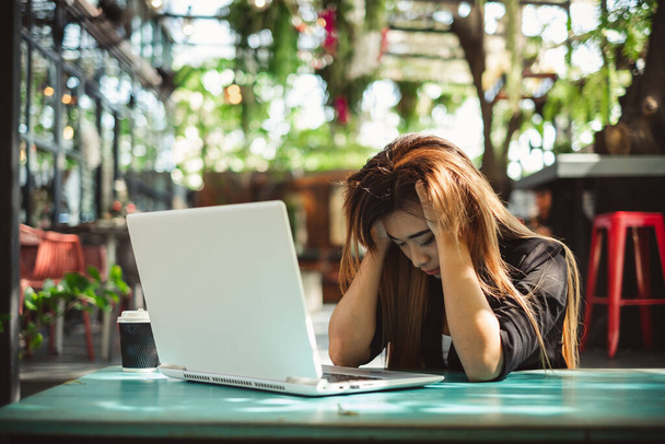Молодая красивая азиатская женщина чувствует боль, усталость, головную боль, и подчеркнул, работая с ноутбуком в кафе кафе, винтажный тон, концепция офисного синдрома - Фото, изображение
