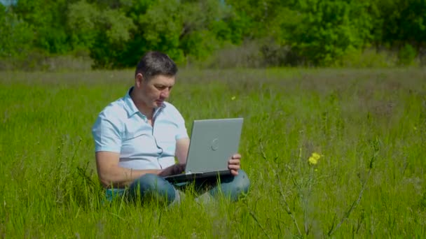Geschäftsmann sitzt hinter einem Laptop im Gras - Filmmaterial, Video