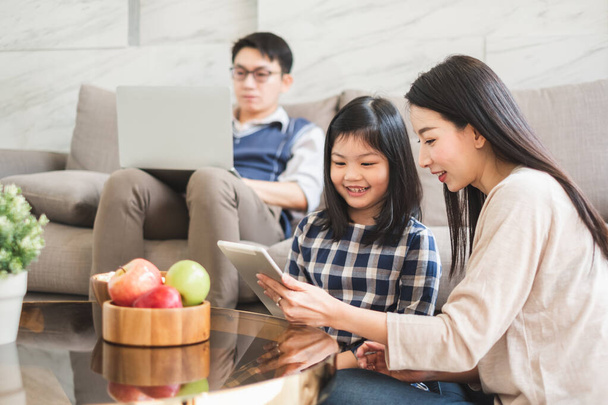 Szczęśliwa azjatycka rodzina za pomocą tabletu, laptopa do gry oglądania filmów, relaks w domu dla koncepcji stylu życia - Zdjęcie, obraz