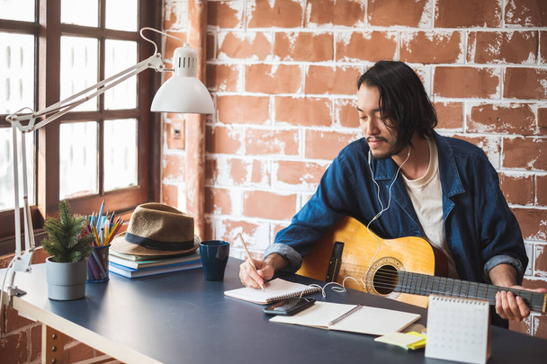 Asiatischer Musiker schreibt Song mit Gitarre - Foto, Bild