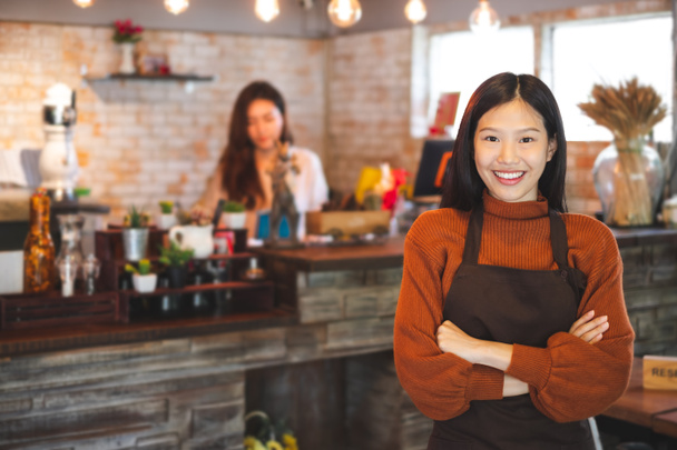 Joven mujer asiática propietaria de un negocio frente a una cafetería / bar / restaurante / cafetería y panadería - Foto, Imagen