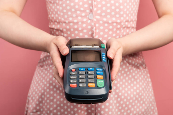 Kobieta w różowej sukience trzymać NFC płatności terminalu bezdotykowego. Karta kredytowa lub telefon Płatności pos urządzenie bankowe, maszyna do kart. - Zdjęcie, obraz