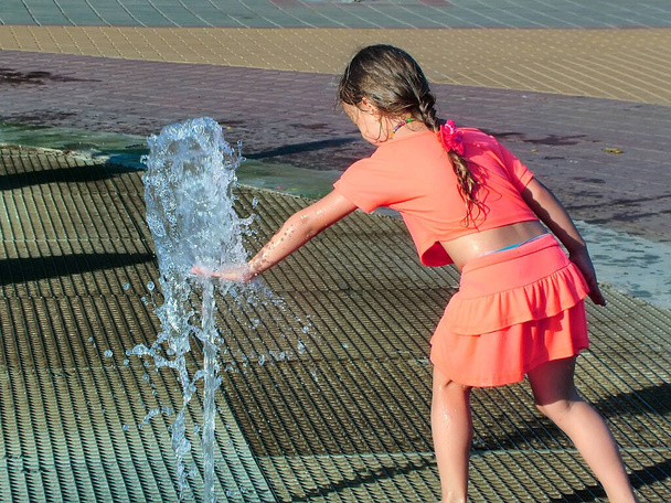 Маленька дівчинка приручає фонтан в літньому міському саду
 - Фото, зображення