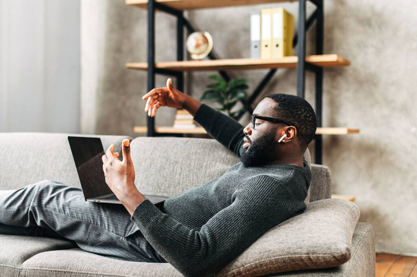 African-American guy lays on sofa with laptop - Foto, Imagem