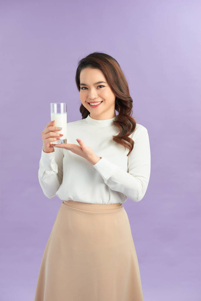 jonge vrouw drinken van melk, geïsoleerd op paarse achtergrond - Foto, afbeelding