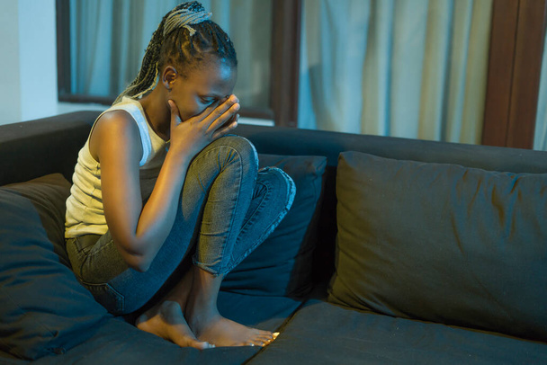 young African American woman suffering depression - sad and depressed black teenager girl in pain at home sofa couch feeling overwhelmed and emotional crying lonely in the dark - Fotó, kép
