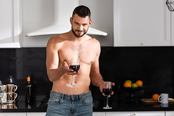 щасливий і м'язистий чоловік тримає окуляри з червоним вином
  - Фото, зображення