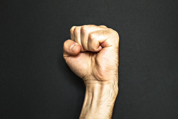 Male fist on a black background. Aggressiveness, masculinity, the concept of challenge. - Photo, Image