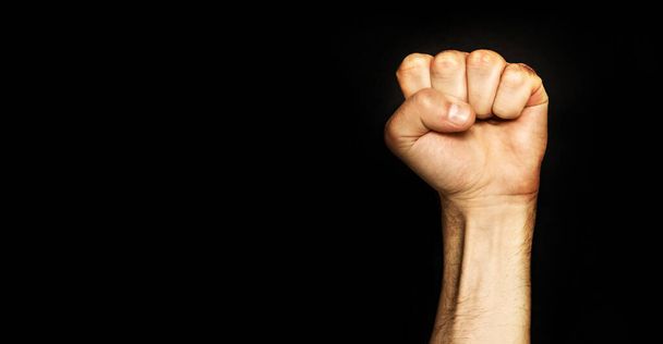 Male fist on a black background. Aggressiveness, masculinity, the concept of challenge. - Фото, зображення