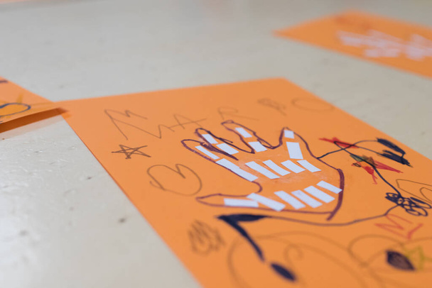 Wissenschaftliche Tätigkeit für Kinder, Zeichnung und Collage der Handknochen. Auf einem orangefarbenen Zettel wurde eine Hand gezeichnet und mit Filzstiften gefärbt. Kreative Aktivitäten für den STEAM-Unterricht - Foto, Bild