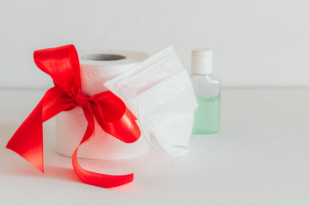 toilet paper with a red bow on a white background. Sanitizer. White medical mask - Photo, Image