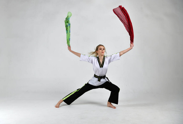 όμορφο κορίτσι ένας μαχητής σε ένα μαύρο και άσπρο κιμονό κάνει ασκήσεις με τη μάχη χρώμα κασκόλ - Φωτογραφία, εικόνα