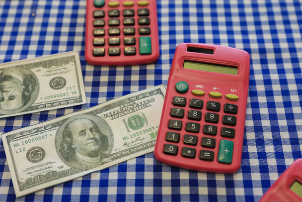 100 Dolars biljetten en rekenmachines op een tafel. Financiën, bedrijfsleven, economie. - Foto, afbeelding