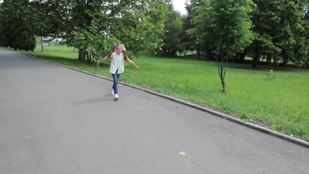Funny girl with pigtails running through park road in front of camera. Happy smiling child in summer. Handheld steadycam flycam movement back shot - Záběry, video