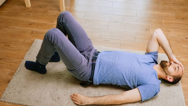 Hombre con dolor de cabeza tendido en el suelo
 - Foto, Imagen
