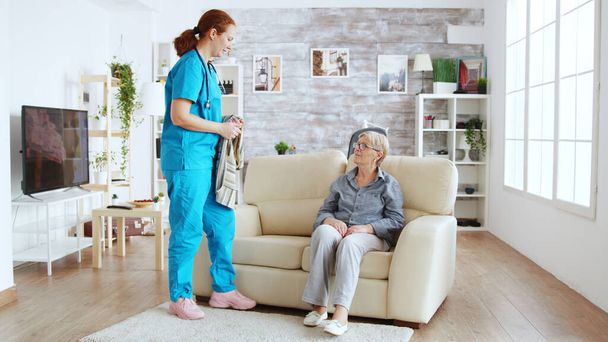 Жіноча медсестра допомагає старшій жінці одягатися
 - Фото, зображення