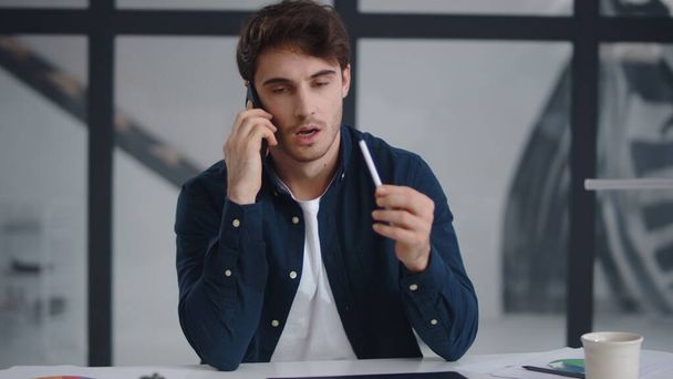 Крупным планом бизнесмен разговаривает на мобильном телефоне в офисе. Гай объясняющий проект
 - Фото, изображение